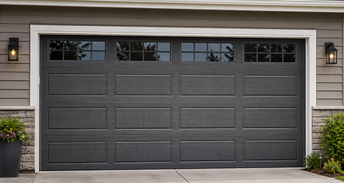 Modern black residential garage door with windows on suburban home exterior